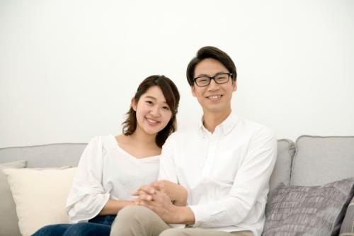 手を取り合いながらソファーに座る夫婦の写真