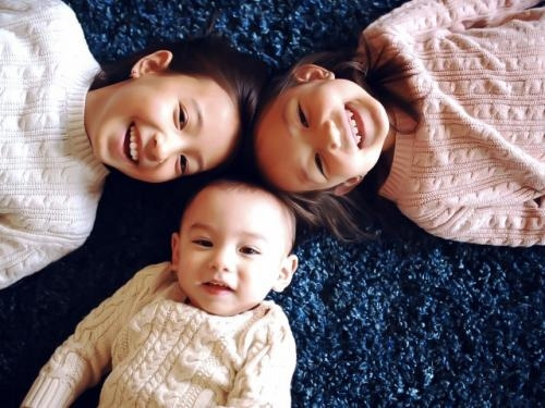 子どもが３人、カーペットに寝そべっている写真
