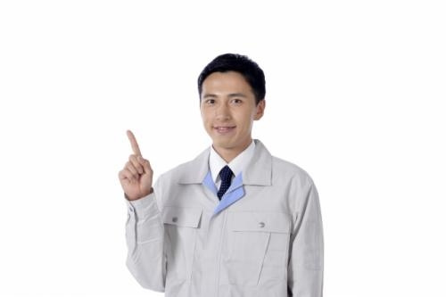 人差し指を立てる作業服を着た男性の写真