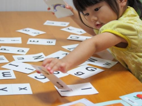 子どもがアルファベットの紙を手にとる写真