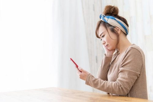女性が部屋でスマホを眺めている写真