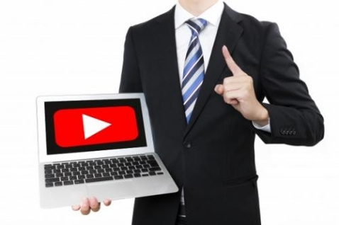 スーツを着た男性が持っているノートＰＣに動画の再生ボタンが映っている写真