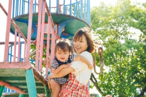 保育園の先生が子どもを遊具から降ろす写真
