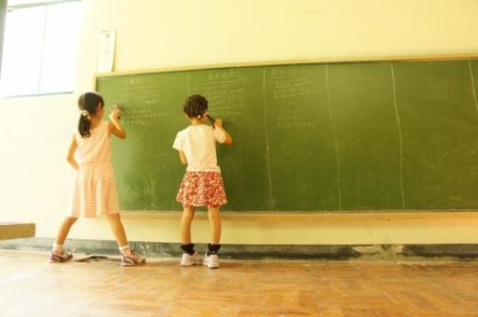 子どもが２人、学校の黒板に答えを書いている風景
