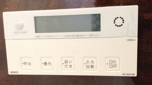 お風呂の操作パネルで追い焚きボタンを押そうとしている写真