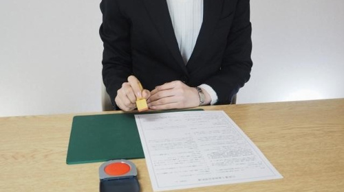 賃貸物件の申込み書に署名・捺印をしている最中の写真