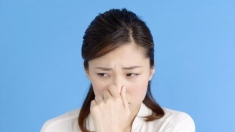 生ごみのニオイに耐え切れず、鼻を指でつまむ女性の写真