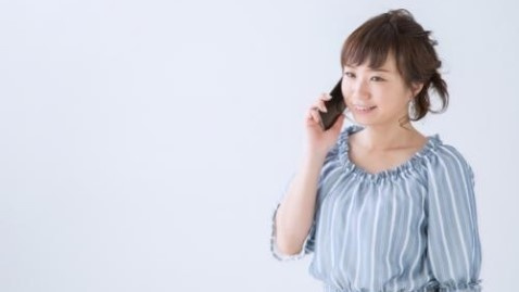 エアコンを取り付けて下さいと携帯で電話している女性の写真