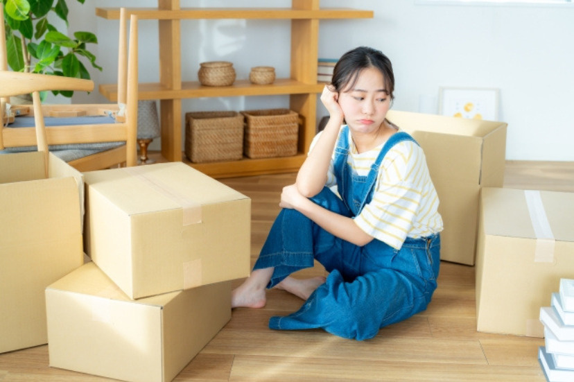 引っ越し最中に何かに悩んでいる女性