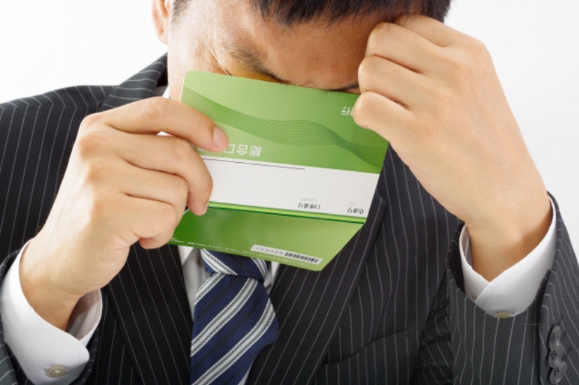 通帳を見て頭を抱える男性