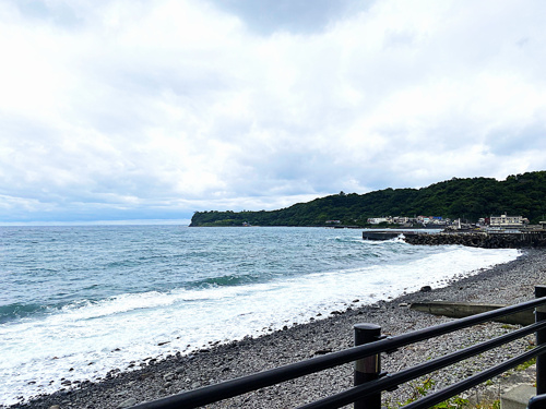 海を背に歩く浦上の写真