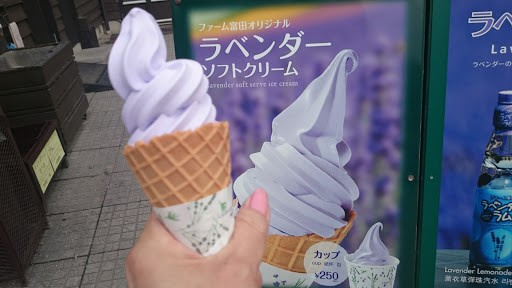 ラベンダー色したソフトクリームを斜めに持っている