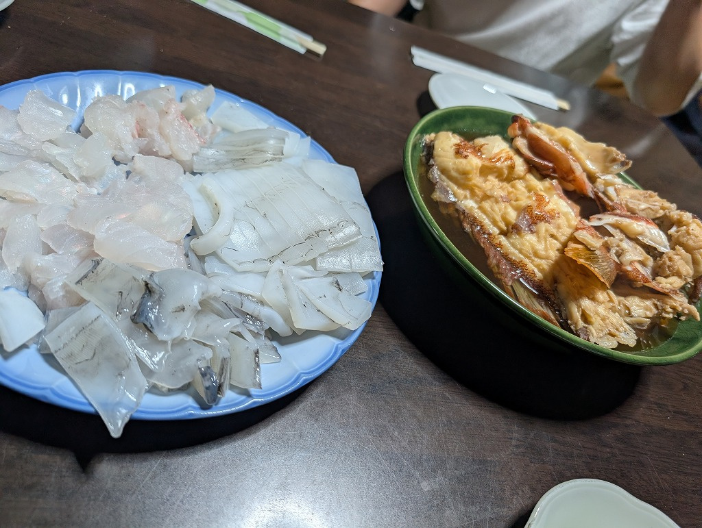 ３枚目：（刺身と煮付け）お皿に綺麗に盛り付けられた新鮮な魚とイカの刺身、そして深鉢に盛られた魚の煮付け料理の写真