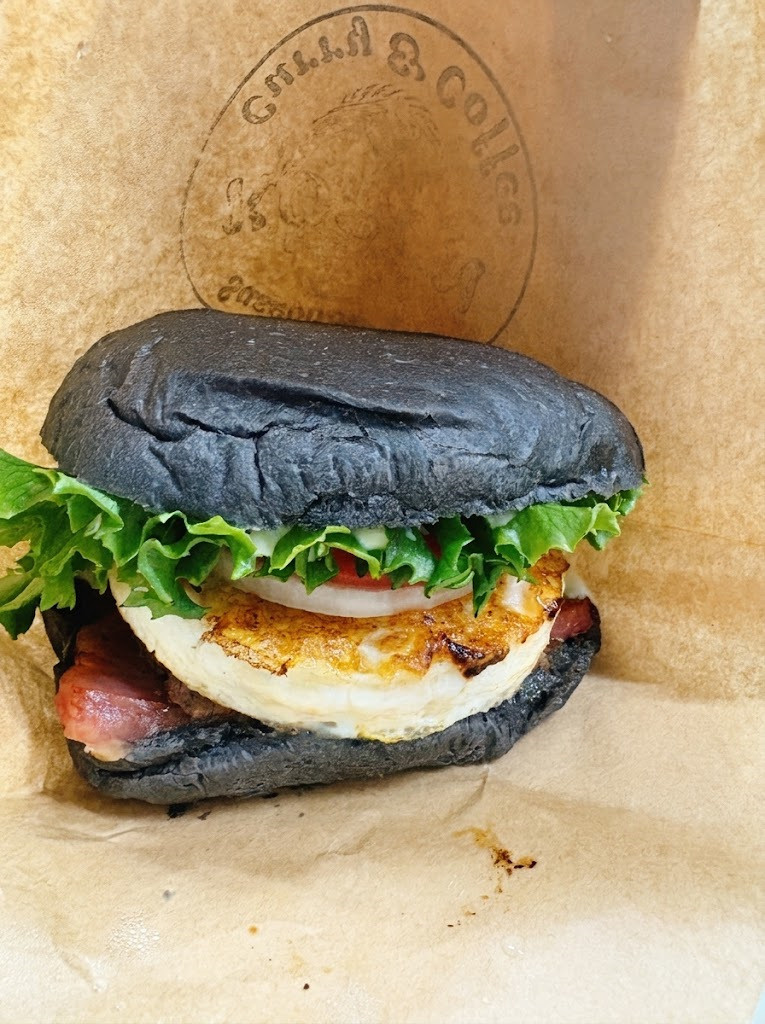 ５枚目：バーガー袋に包まれた、黒いバンズとジューシーな具材が詰まったハンバーガーのアップ写真